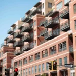 Modern brick apartment building with balconies and traffic light.